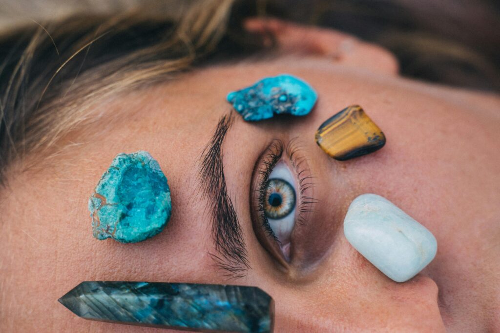 pexels-photo-6512485-6512485 Close-up of a person's eye surrounded by vibrant healing stones on skin for relaxation therapy.