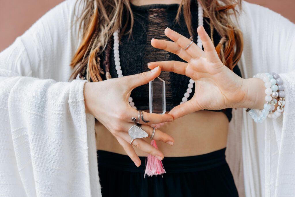 pexels-photo-6932081-6932081 A woman wearing jewelry holds a clear healing crystal, symbolizing spiritual wellness.