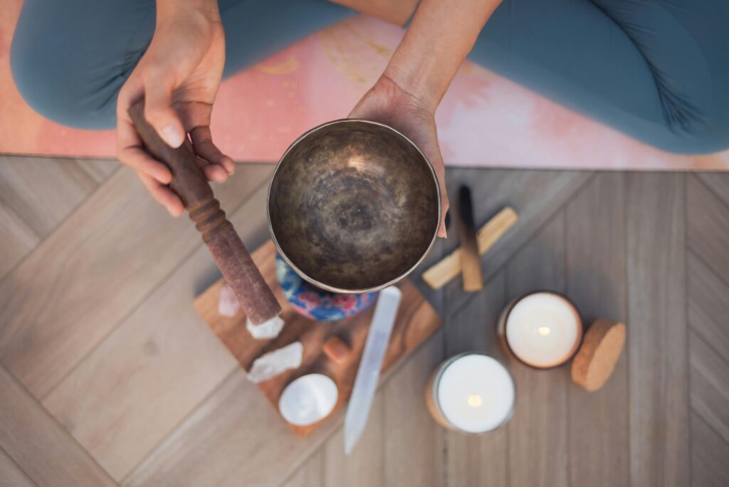 pexels-photo-8391659-8391659 A person holding a Tibetan singing bowl on a yoga mat with meditation tools.