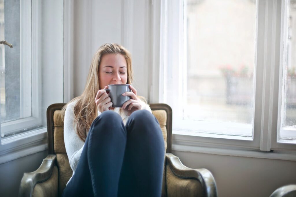 pexels-photo-846080 Woman enjoying a warm drink in a cozy armchair by a window, embracing relaxation.